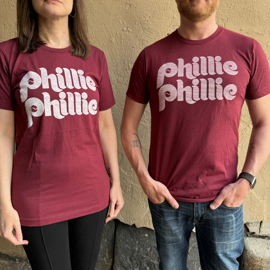 Two people standing side by side, both in maroon exit343design shirts emblazoned with