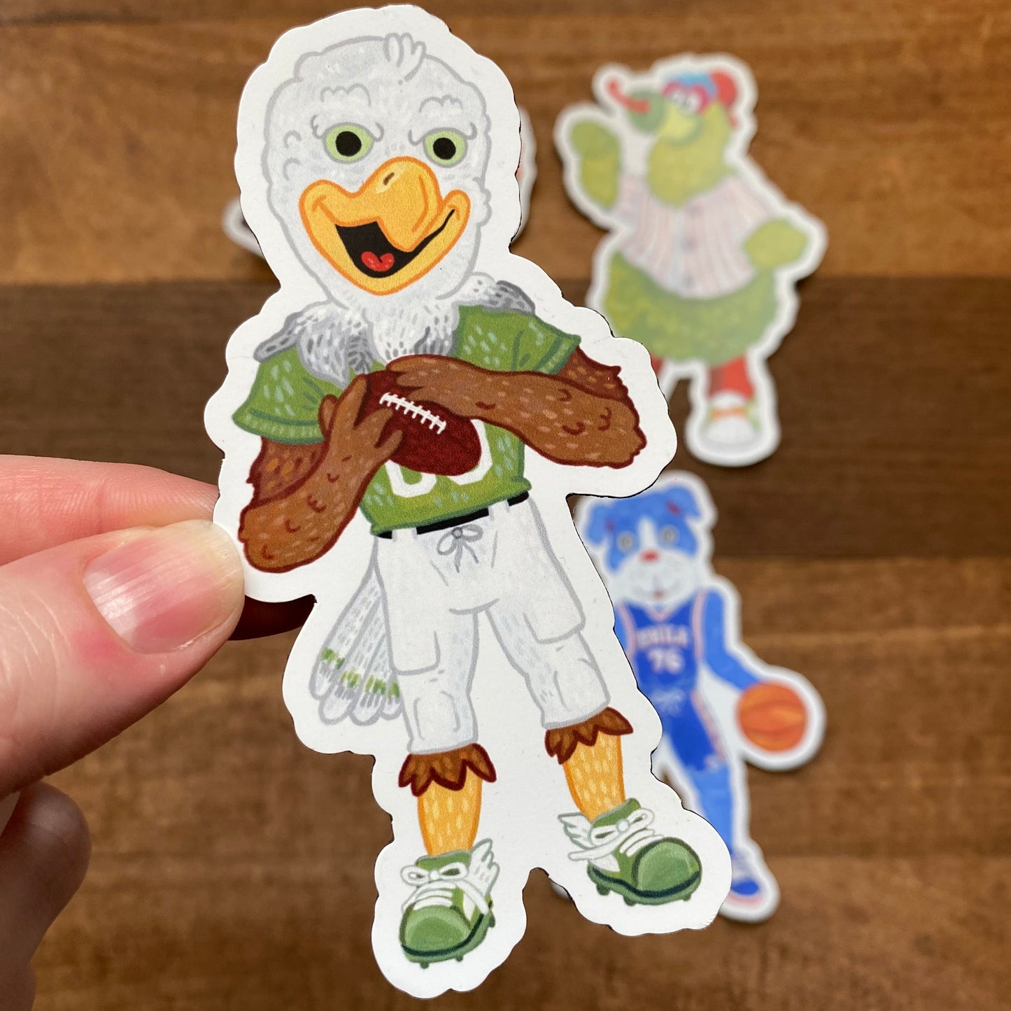 Hand holding a Philly Mascot Magnet of an anthropomorphic duck dressed in sports attire and holding a football by Jamie Bendas.