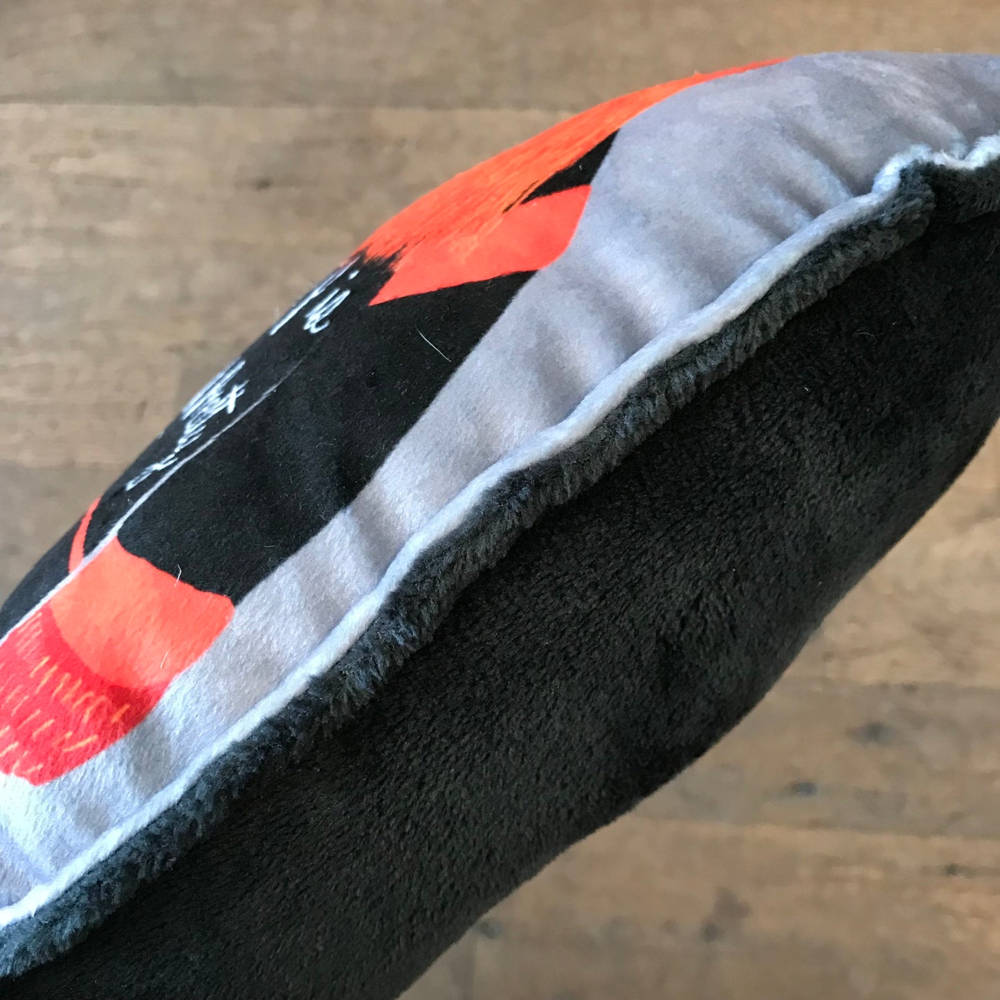 A close-up view of an Ana Thorne Gritty plushie pillow with a hole at the heel, revealing the mascot, placed on a wooden floor.