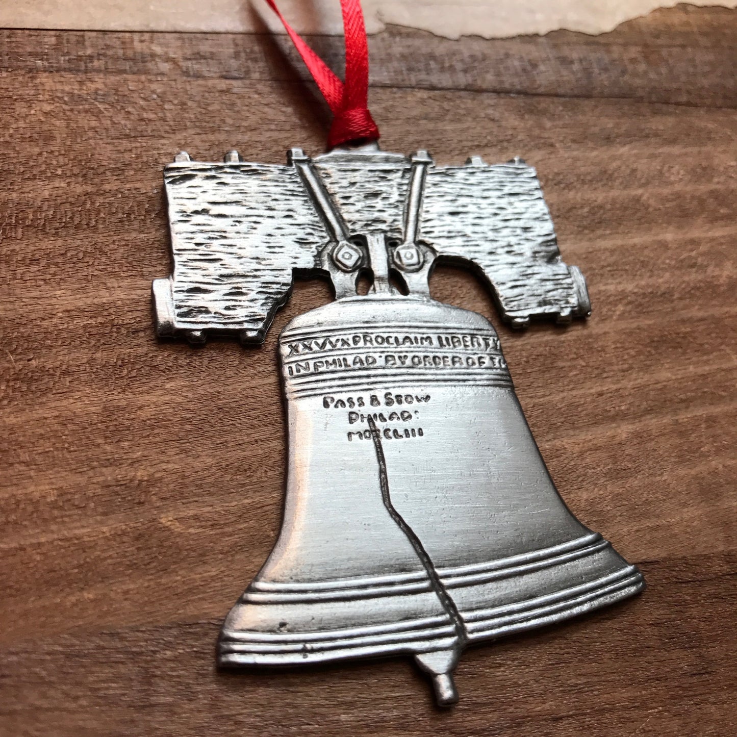 A LOVE & Liberty Bell ornament by Aristocraft Pewter, featuring intricate details and inscriptions, displayed on a wooden surface.