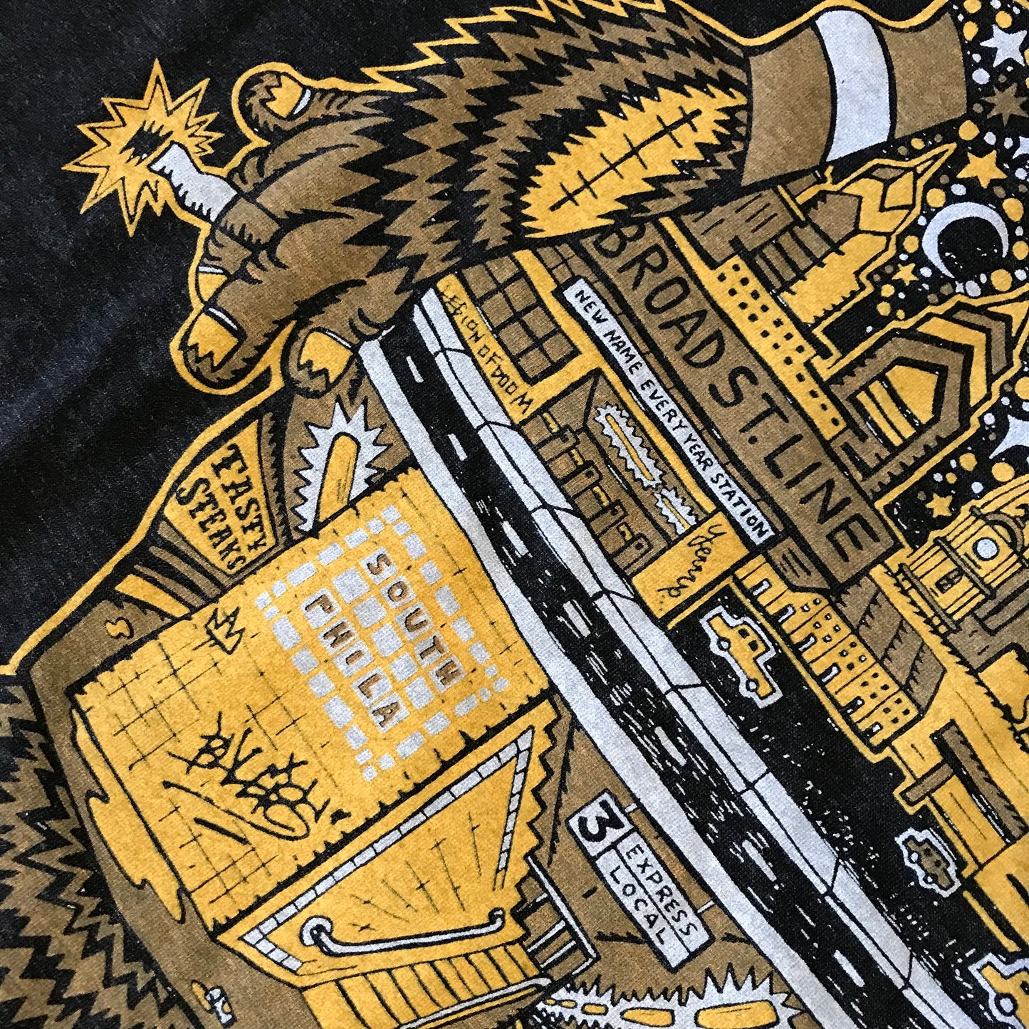 A Gritty T-Shirt design by Paul Carpenter on a Tri-Blend t-shirt depicting a stylized hand holding a radio transmitter tower, with text elements and a cityscape in a yellow and black color scheme.