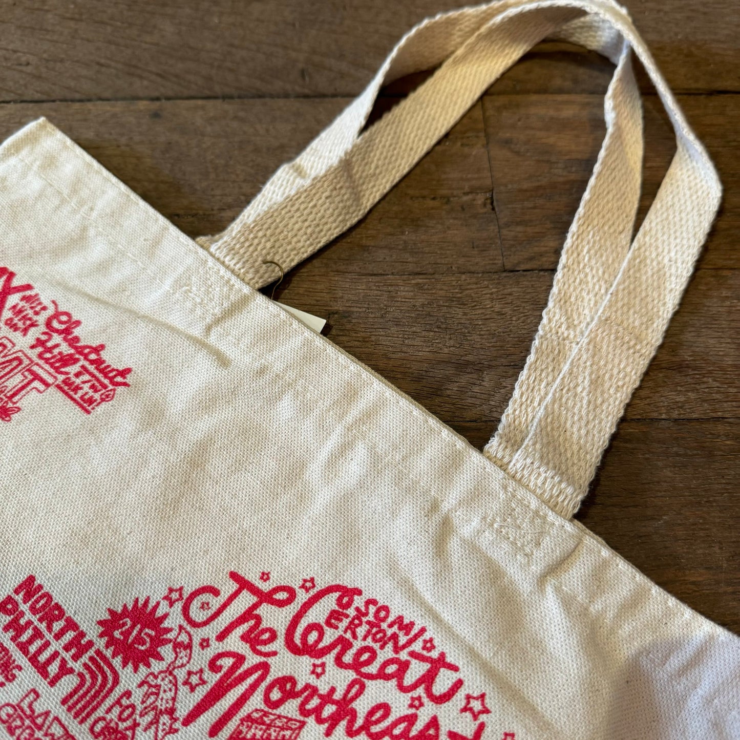 A Paul Carpenter LOVE tote bag with red text and graphics on a wooden surface.