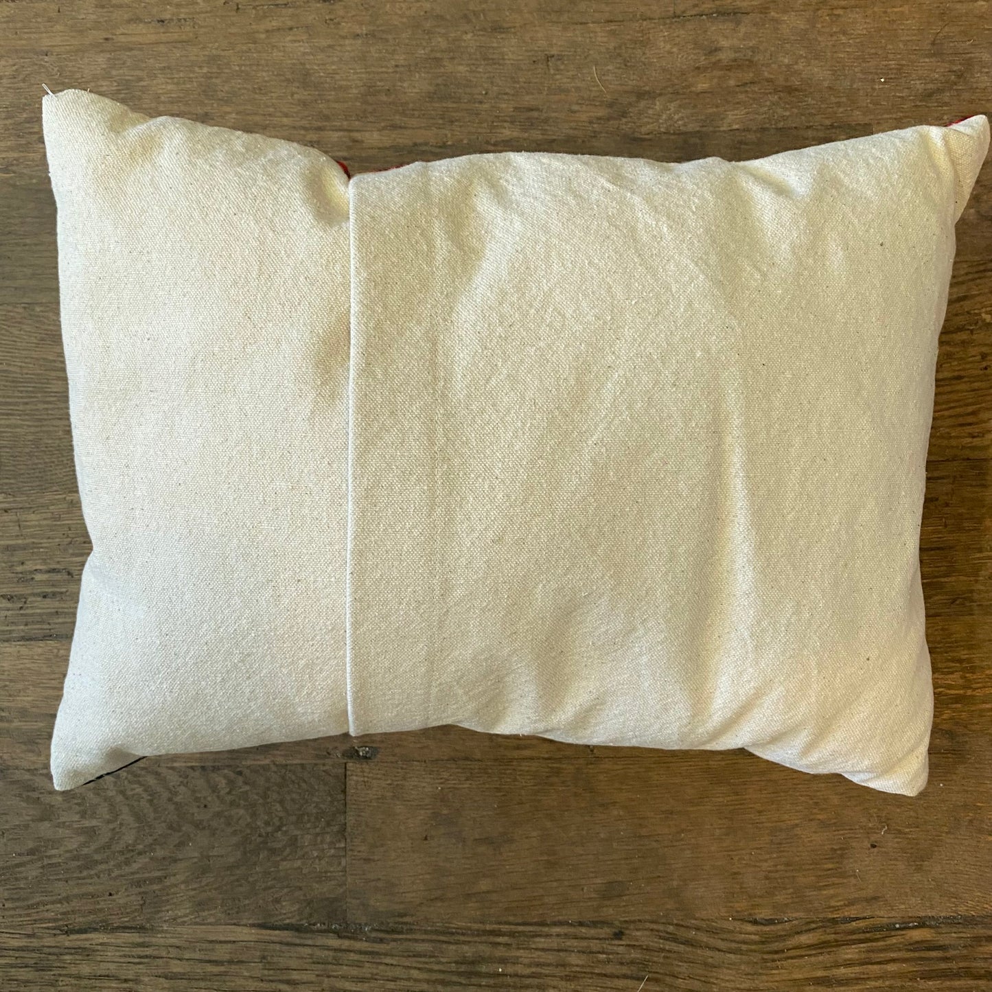 A Holiday Plaid Pillow, crafted with care by The Pillow Works, is placed on a wooden surface.