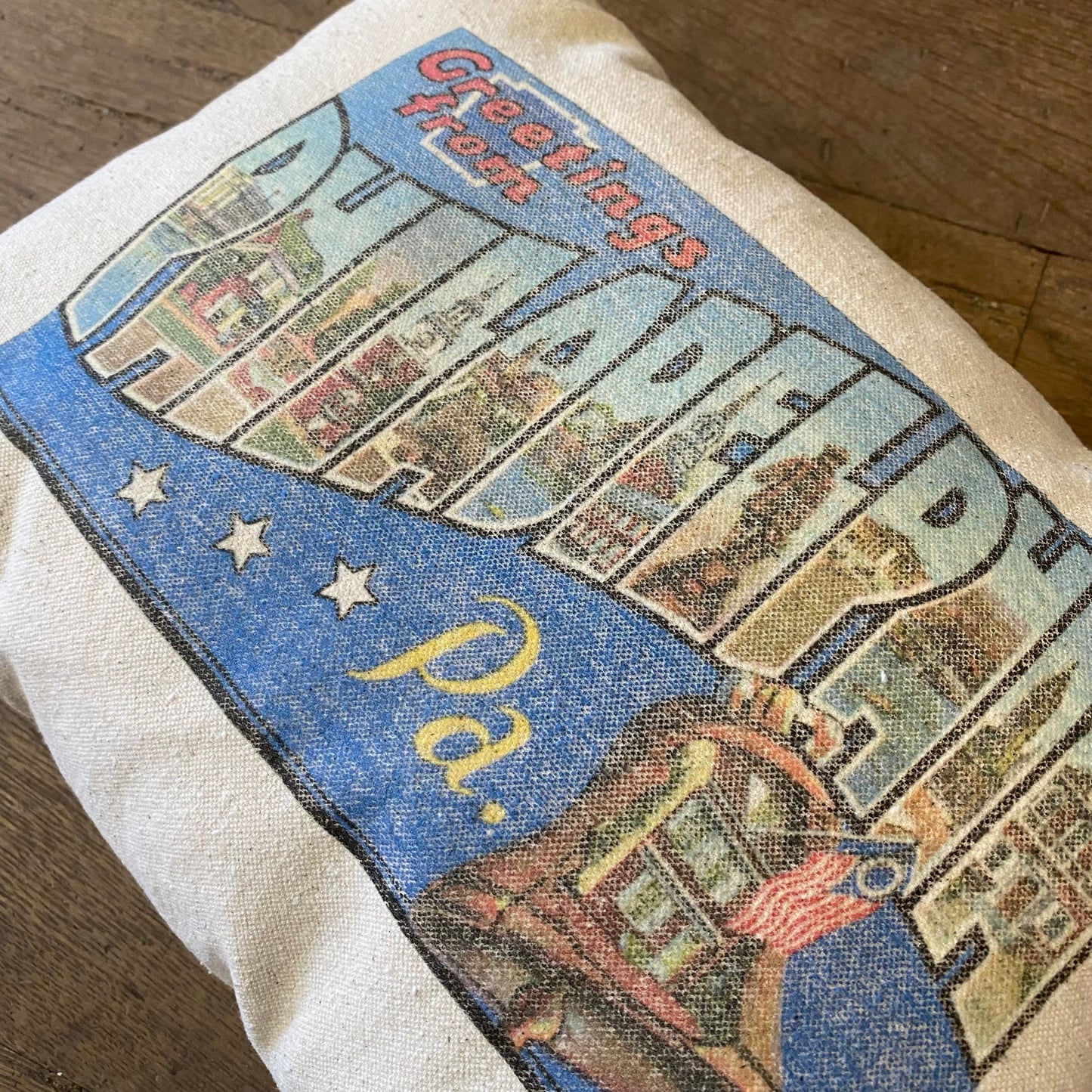 A vintage fabric Philly Postcard Pillow tote bag featuring a colorful "Greetings from Philadelphia, PA" postcard design with iconic landmarks and an unbleached cotton American flag by The Pillow Works.