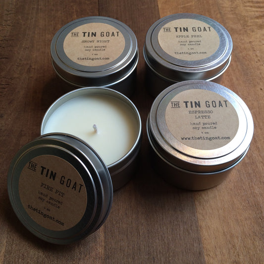 Four Tin Collection soy candles in tin containers with lids, labeled