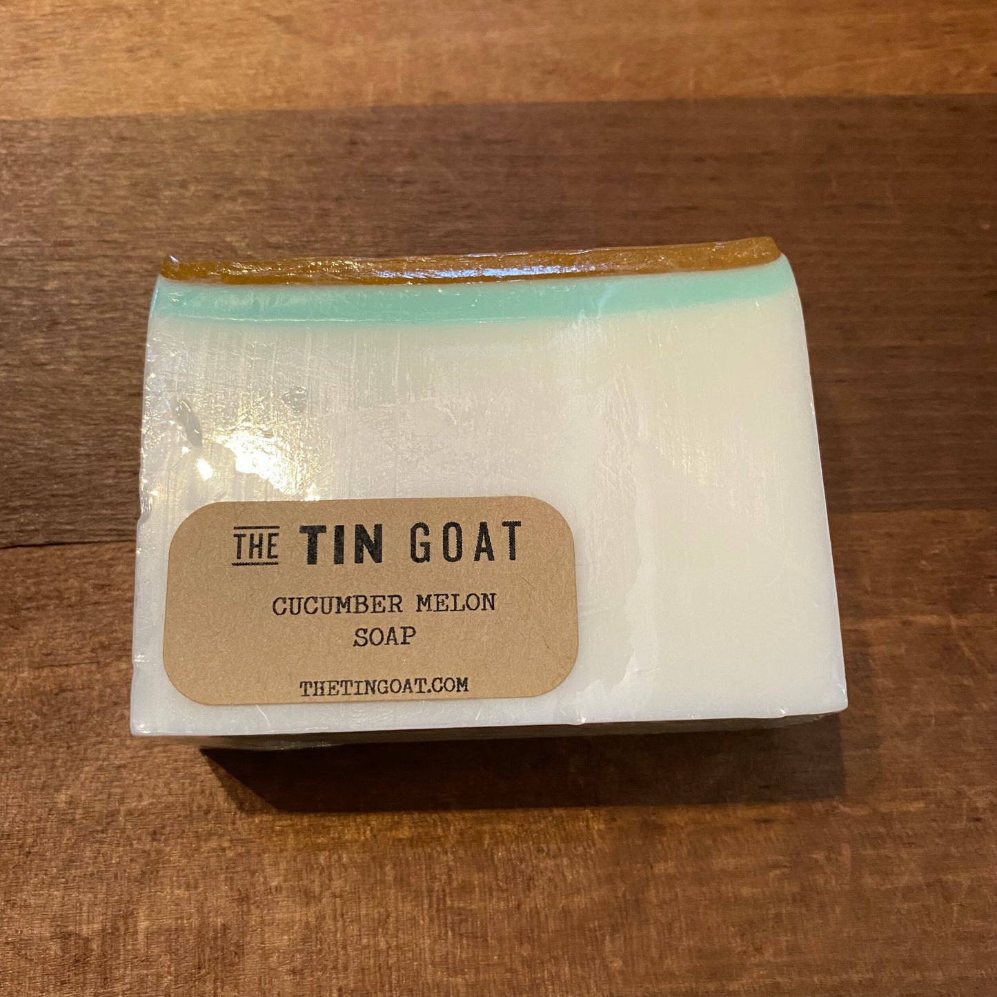 A bar of fragrant cucumber melon scented soap from The Tin Goat, placed on a wooden surface.