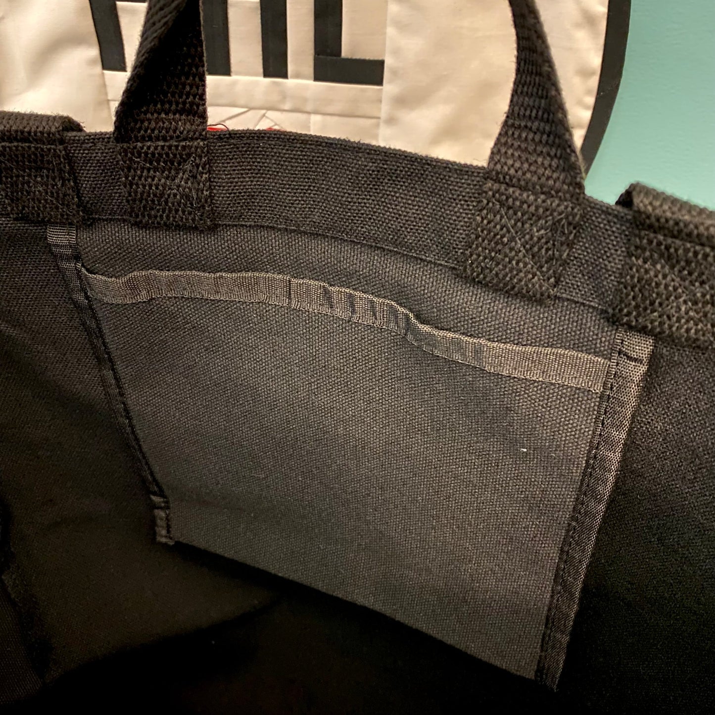 Close-up view of a black Philadelphia Patch Tote Bag by Tote Jawn with detailed stitching on the handle.