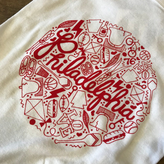 A red and white graphic print onesie featuring various sports-related icons, the Liberty Bell, and the word
