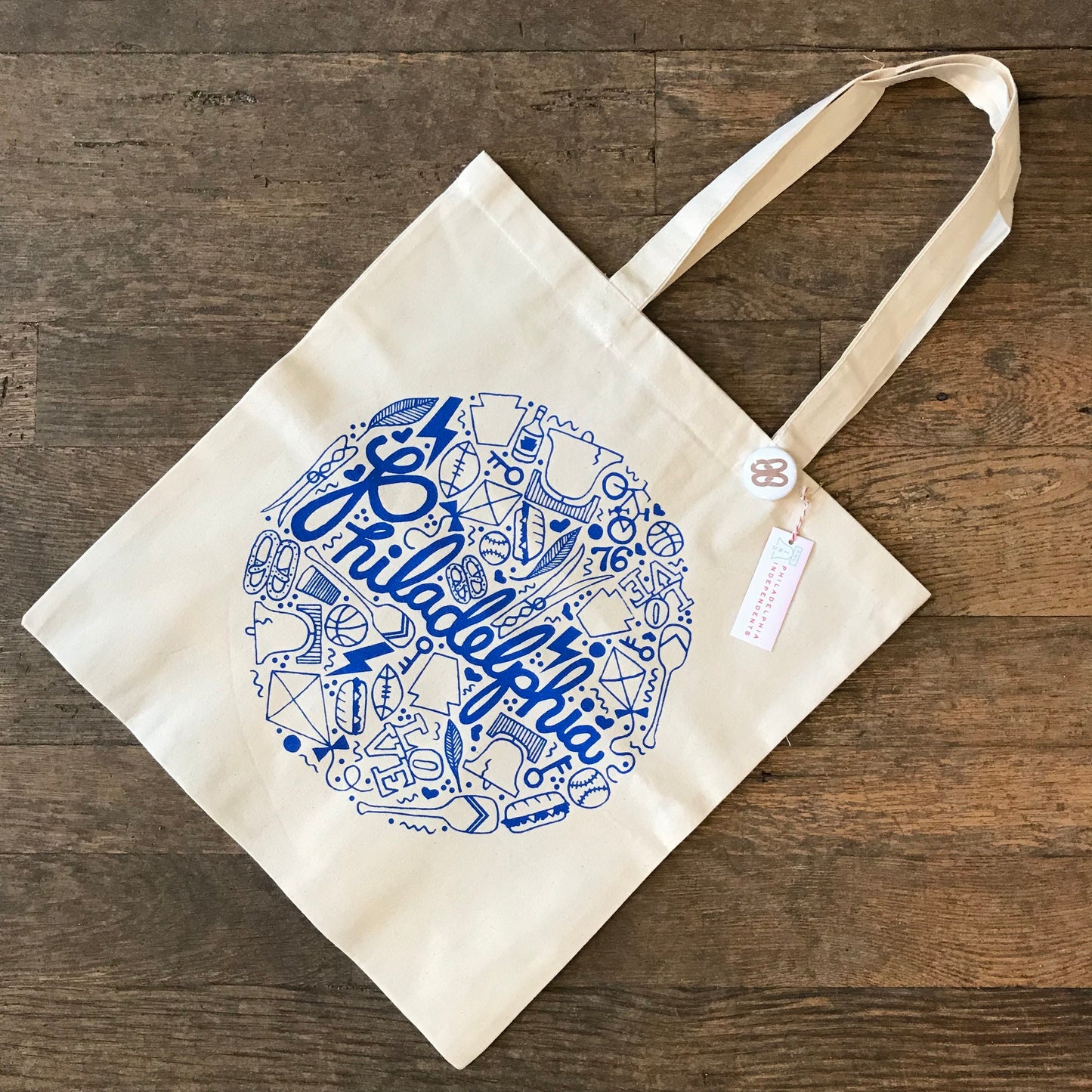 A canvas exit343design Philadelphia tote bag with a blue graphic design featuring symbols such as the Liberty Bell and text related to Philadelphia.