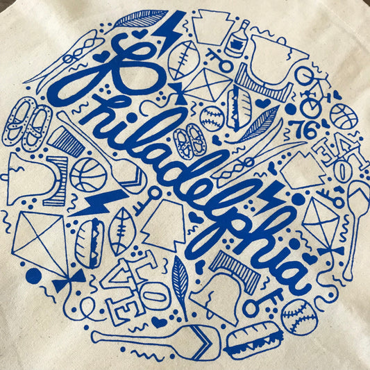 A circular design featuring iconic symbols such as the Liberty Bell and text related to Philadelphia on a fabric surface of a exit343design Philadelphia Tote Bag.