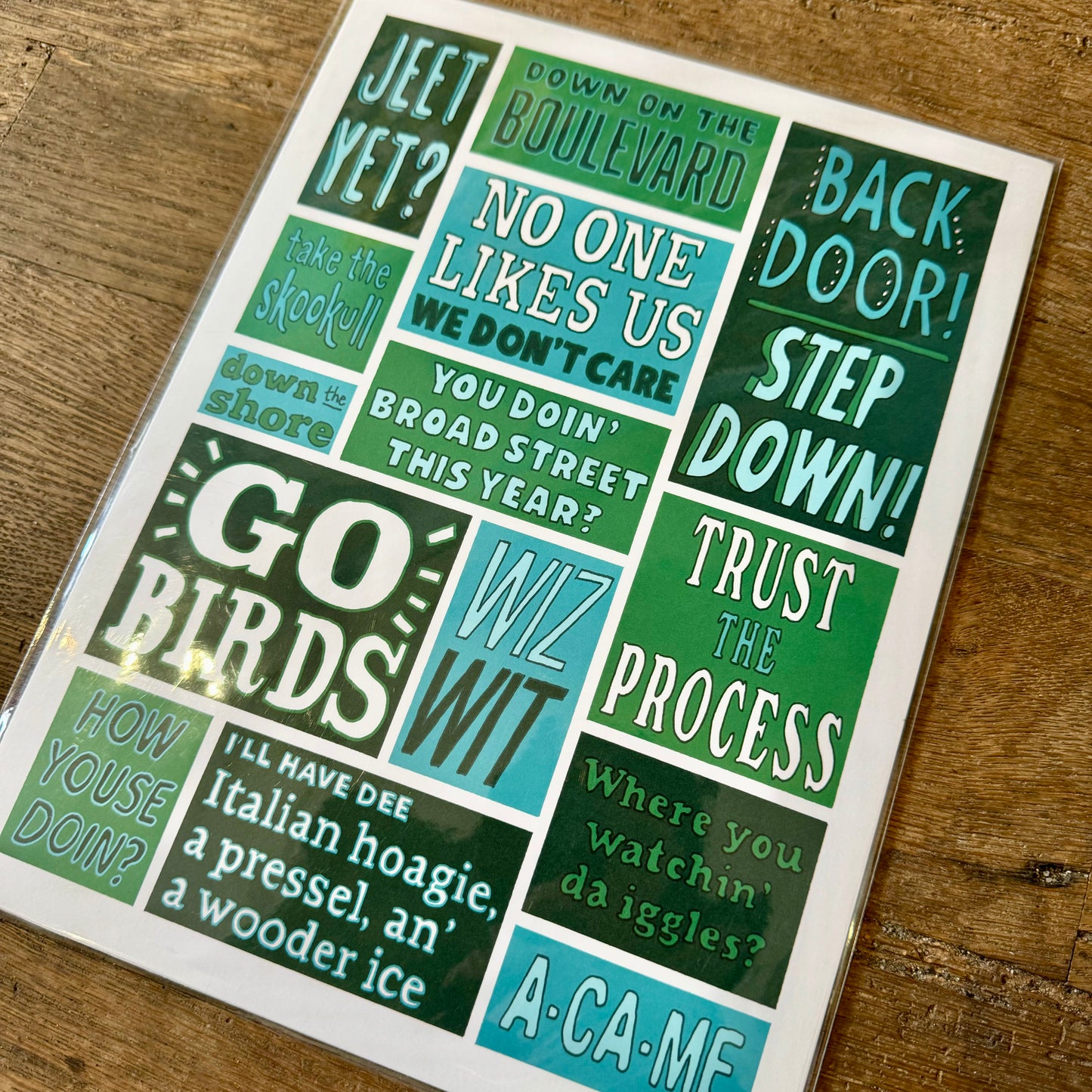 Description: Image of Philadelphia Prints by Kate Otte featuring various Philly-themed phrases and slang in bold, colorful text. Phrases include "GO BIRDS," "NO ONE LIKES US, WE DON'T CARE," and "STEP DOWN.