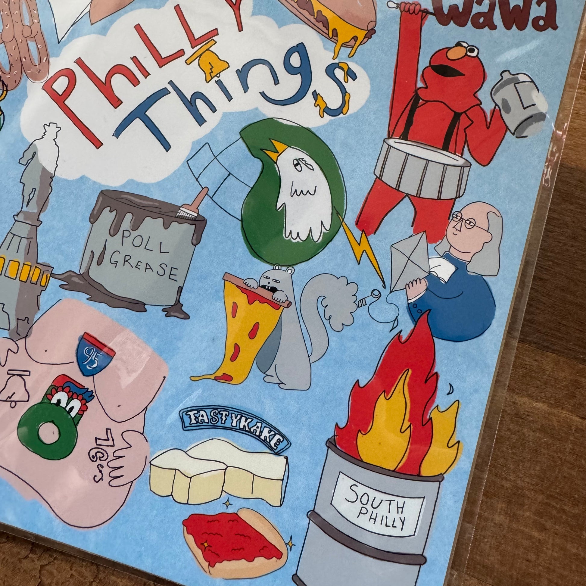 The Philly Things Print from LizPopArt is a colorful illustration depicting various Philadelphia icons and landmarks, including the Liberty Bell, TastyKake, Elmo with a drum, South Philly flame, a cheesesteak, and the word "Philly Things." Printed on professional matte premium paper, this vibrant piece captures the essence of Philly prints.