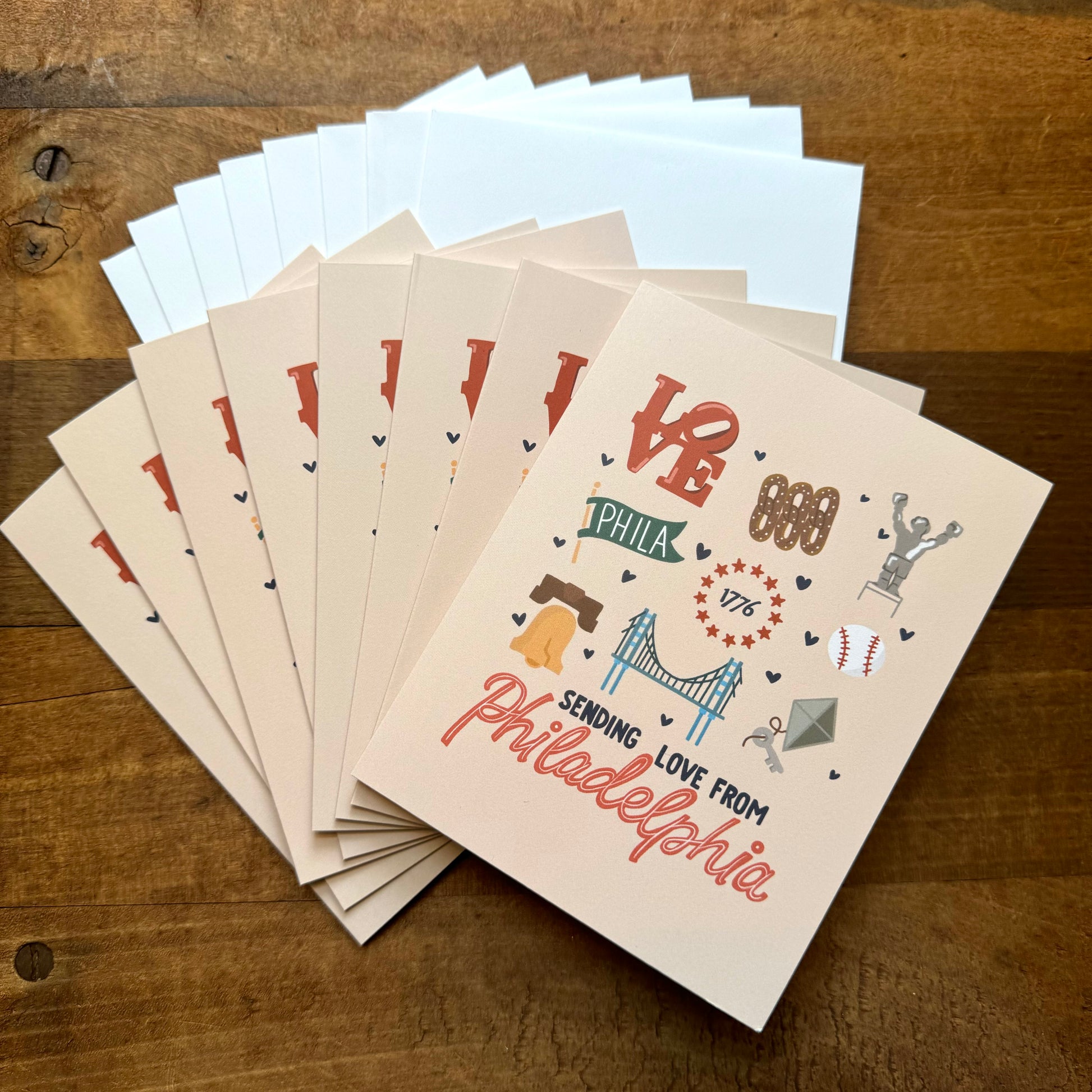 The Philadelphia Notecard Pack by Parcel Island features a stack of blank cards with "Sending Love from Philadelphia" written on them, showcasing various Philly flair icons like the Liberty Bell, LOVE sculpture, and a bridge.