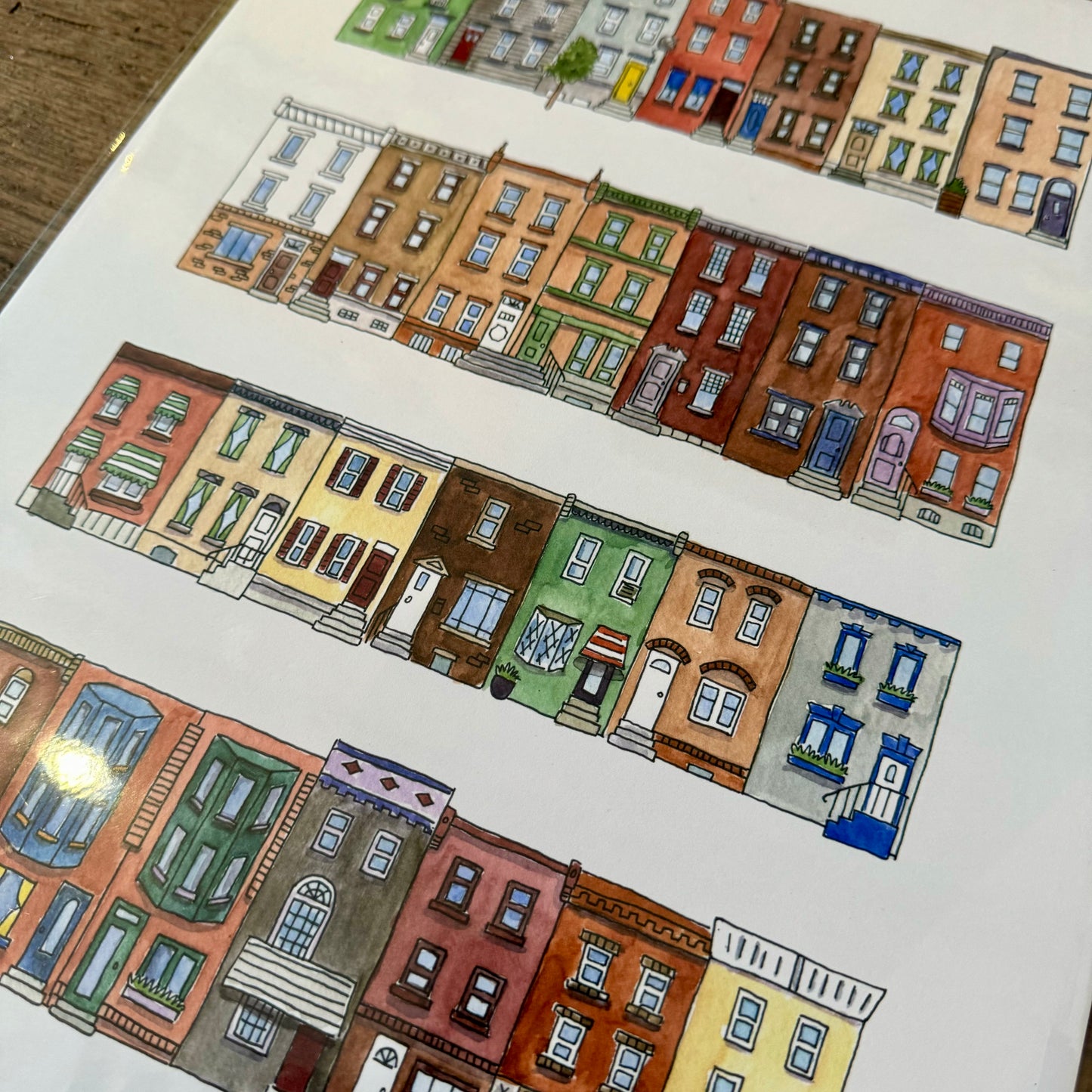 A detailed illustration of four rows of colorful row houses, each showcasing unique architectural features and vibrant colors, drawn on white paper. Perfect for fans of Philadelphia Prints by Kate Otte.