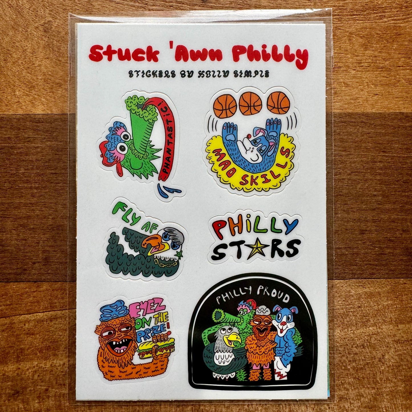 A sheet of "Philly Sticker Packs" by Holly Simple showcases an array of Philly-themed designs, including dragons, street art, basketballs, and phrases like "Philly Stars" and "Philly Proud." These distinctive sticker packs celebrate the vibrant spirit of Philadelphia.