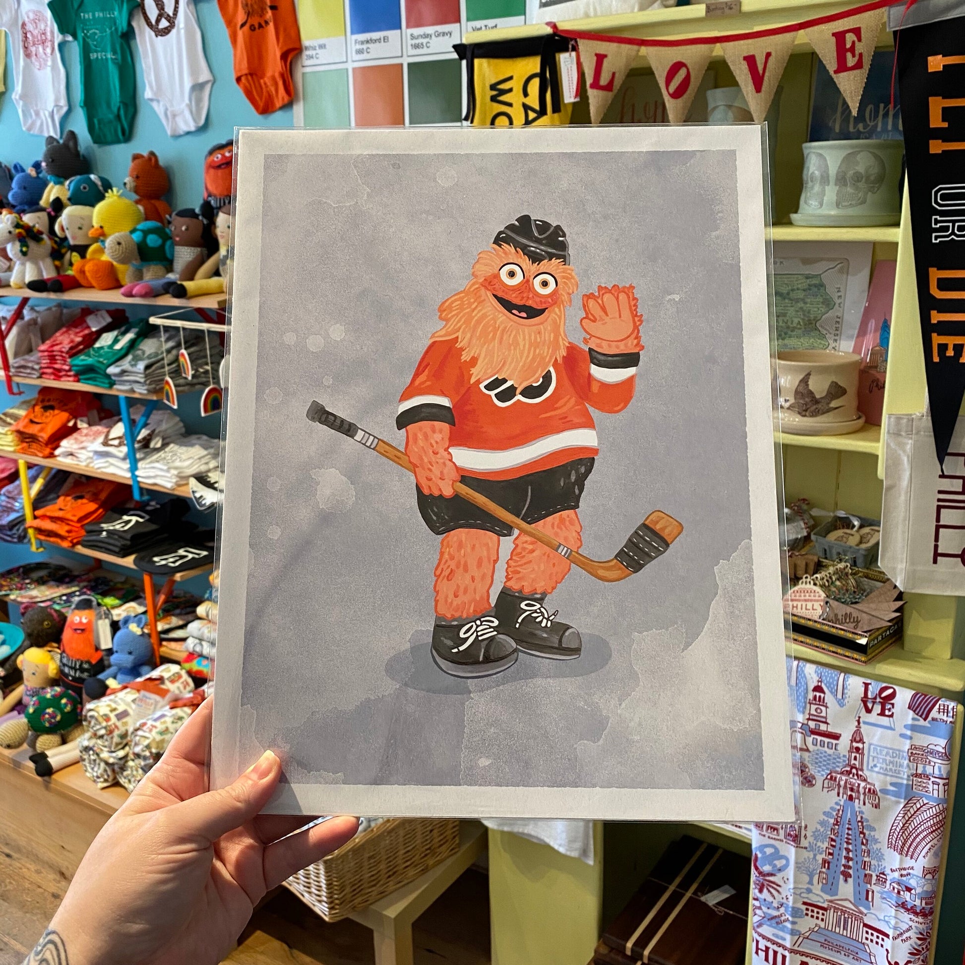 Illustration of a cartoon hockey player with orange fur, holding a hockey stick, presented on Philly Mascot Prints by Jamie Bendas.