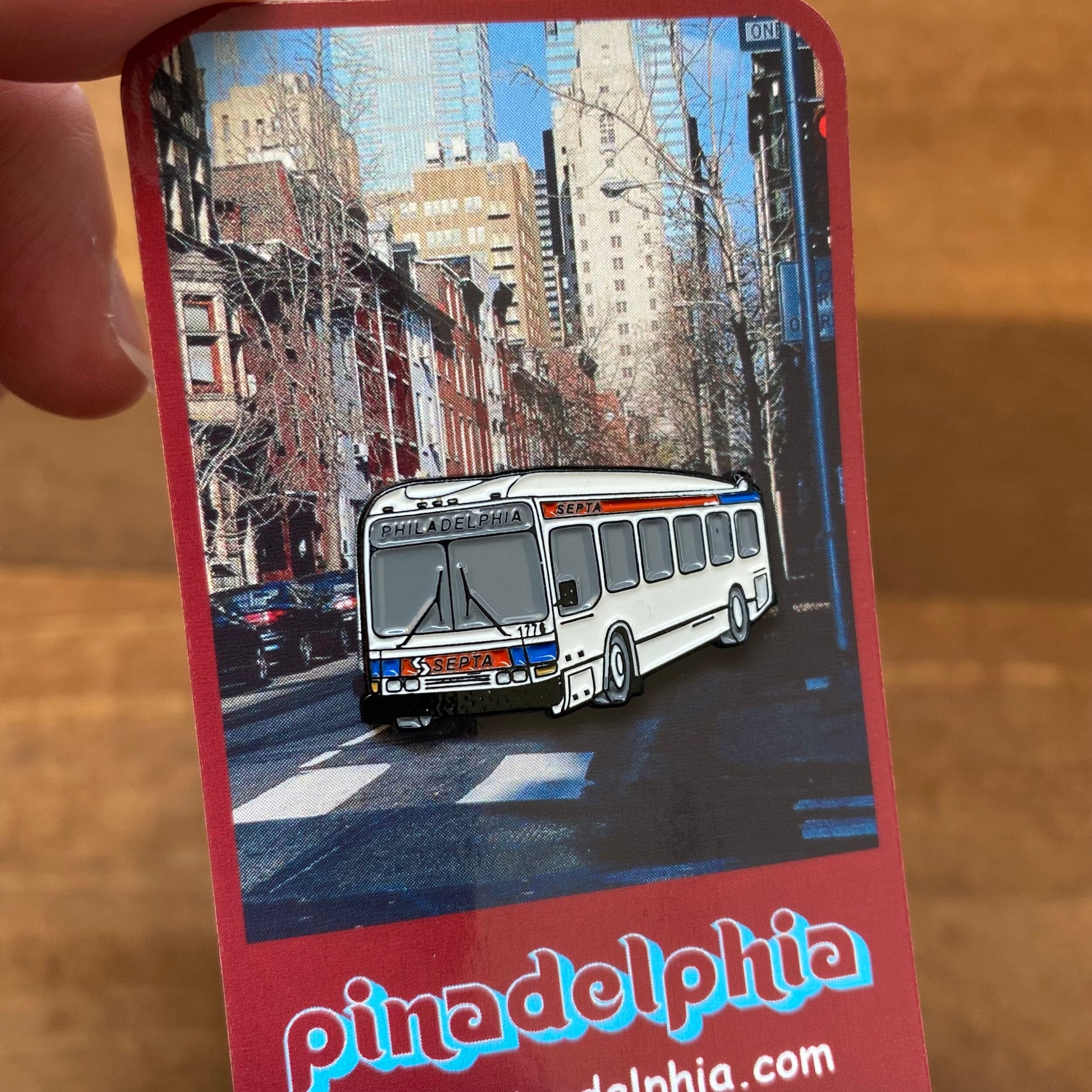 A person holding a brochure featuring an image of a septa bus in Philadelphia, adorned with an array of Pinadelphia's Philly-Themed Enamel Pins II.