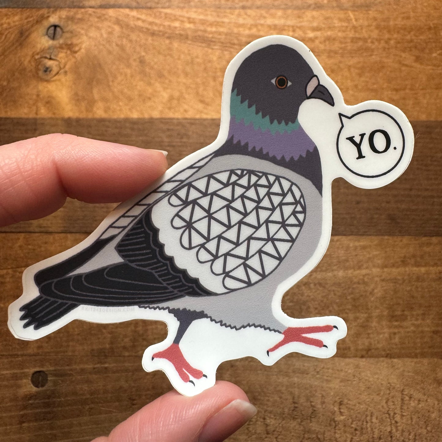 A hand holding a Philly-themed, pigeon-shaped vinyl sticker with the word "yo." written in a speech bubble, made by exit343design Philly Stickers.