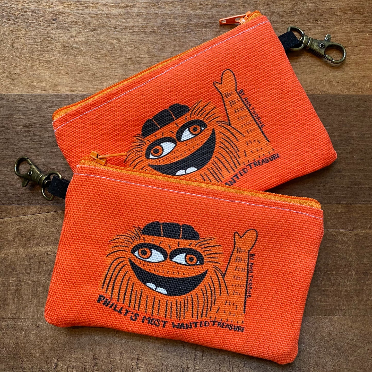 Two Gritty & Phanatic zipper pouches with a graphic of a cartoon cat face and the inscription "Philly’s Most Wanted Treasure" by Ana Thorne.