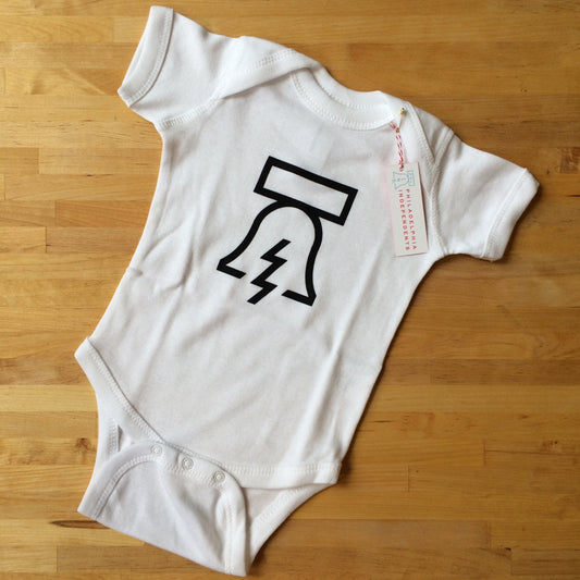 Bell & Bolt Baby Onesie with a minimalist tree design, placed on a wooden floor, and inspired by Philadelphia Independents.