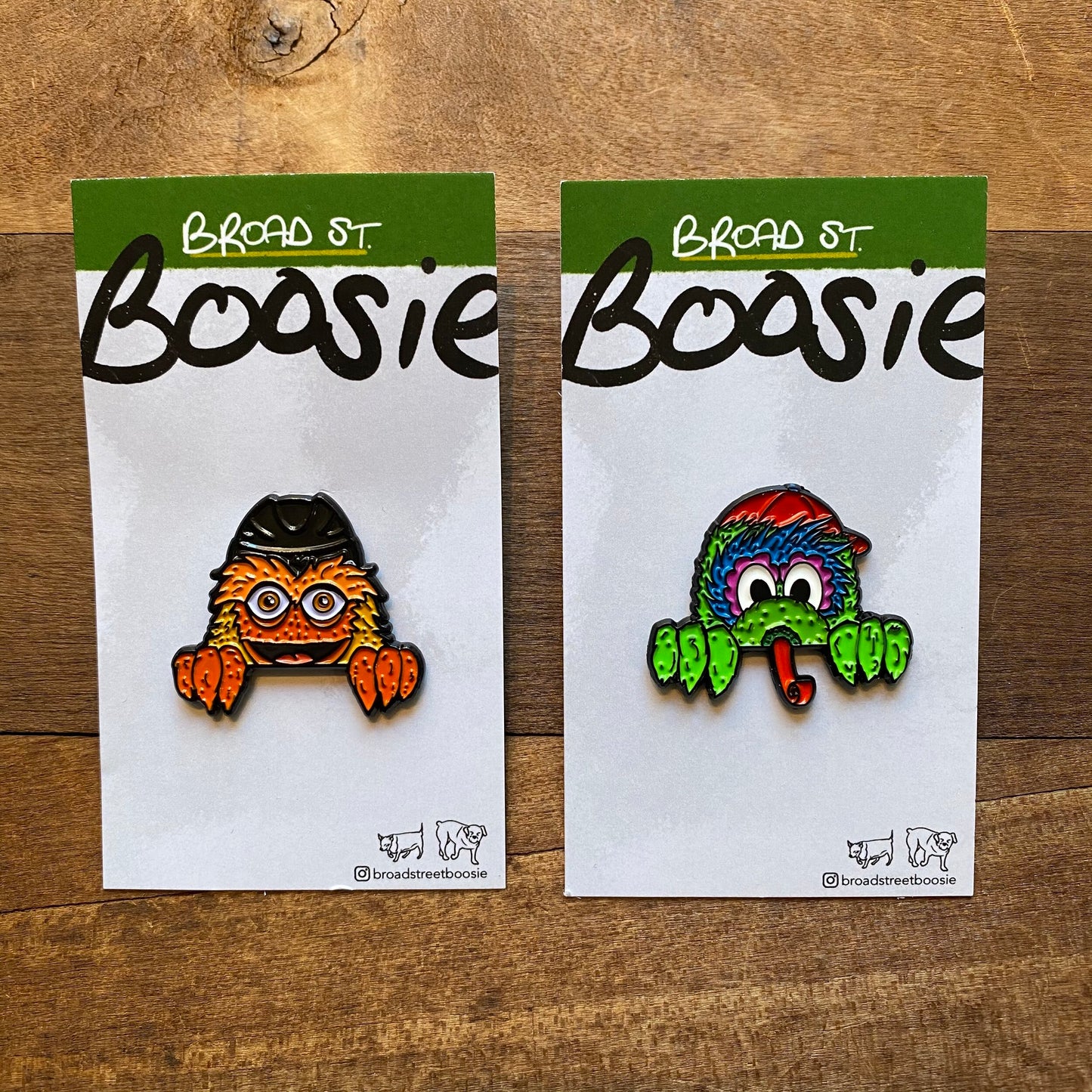 Two colorful, whimsical Gritty & Phanatic enamel pins displayed on Broad Street Boosie branded cardboard backings.