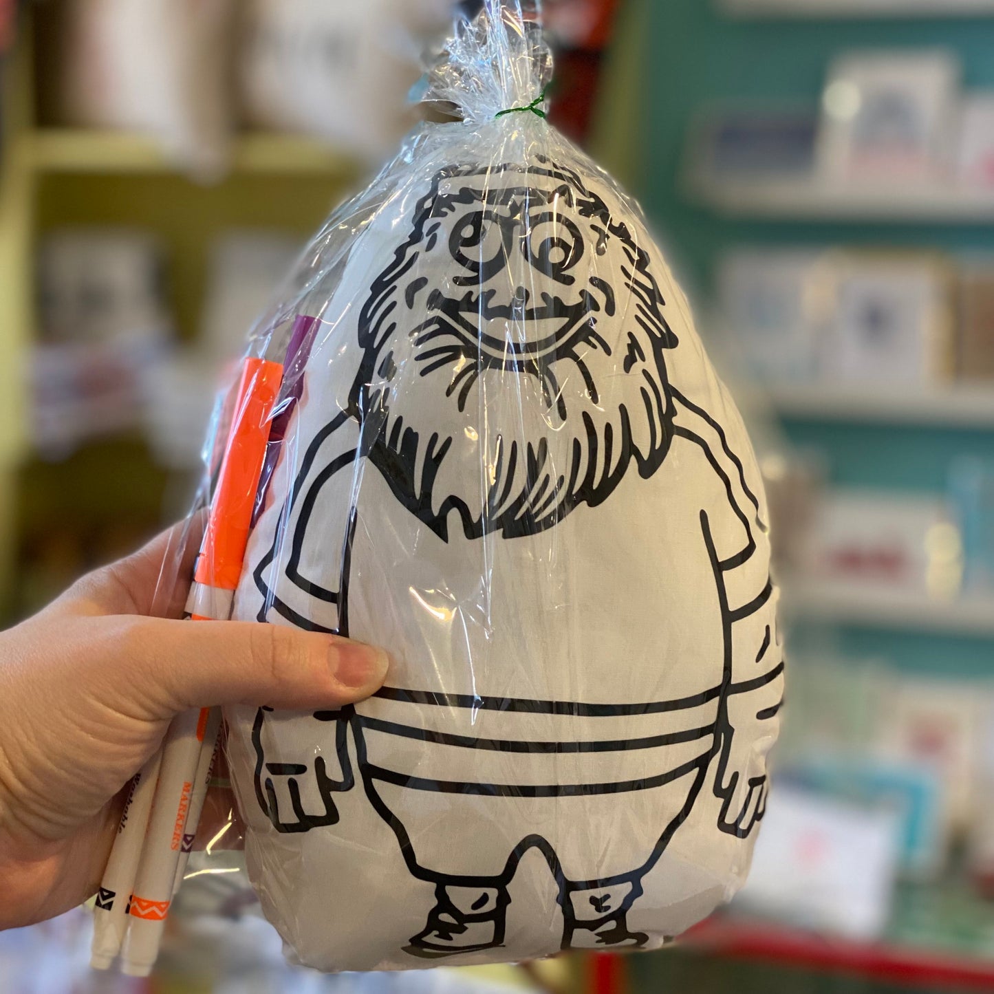 A hand holding a packaged Washable Kits inflatable toy with a printed design of the Gritty, in a retail store setting by Doodle Jawnz.