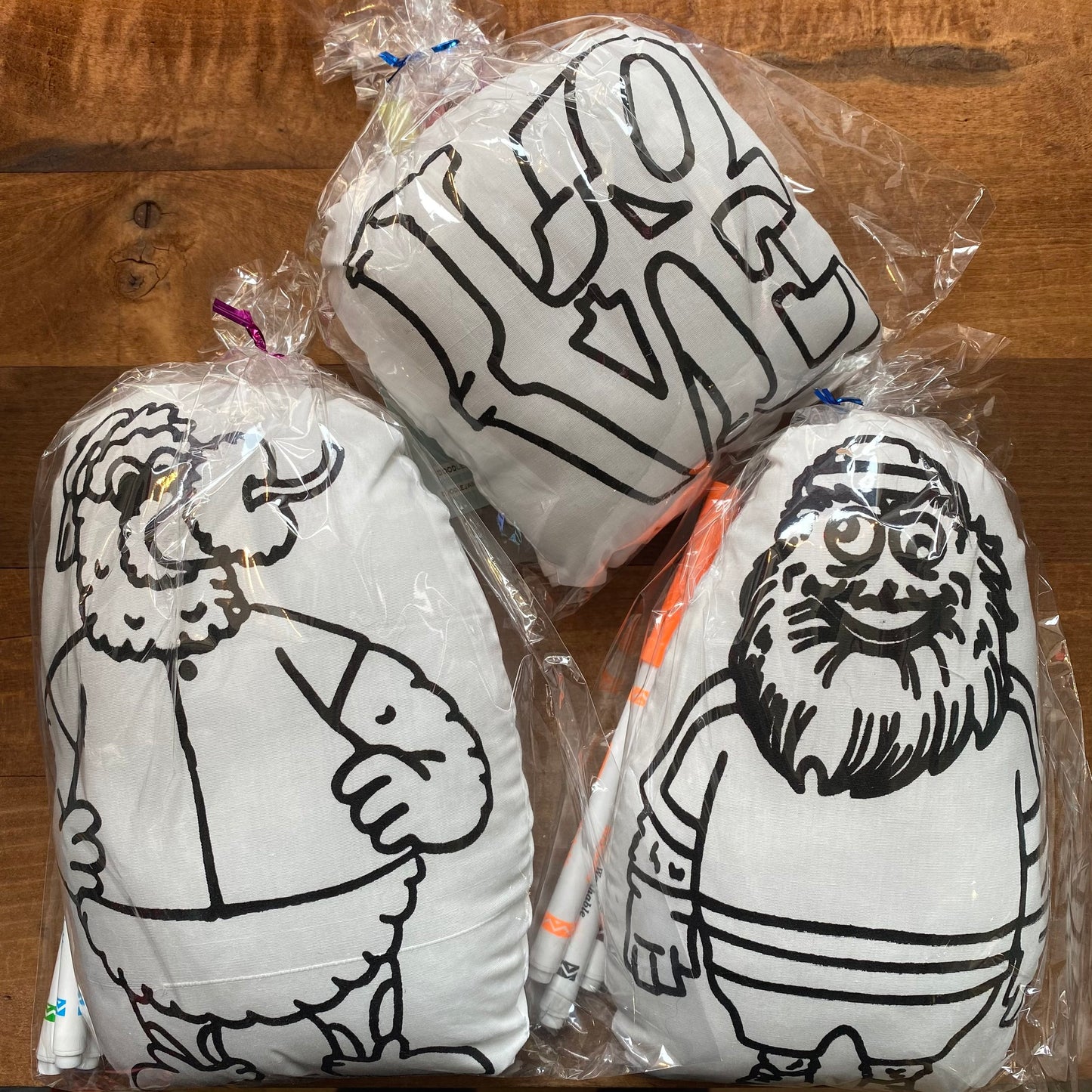 Three vacuum-packed Washable Kits featuring gritty, black-and-white cartoon illustrations of characters, displayed on a wooden table.