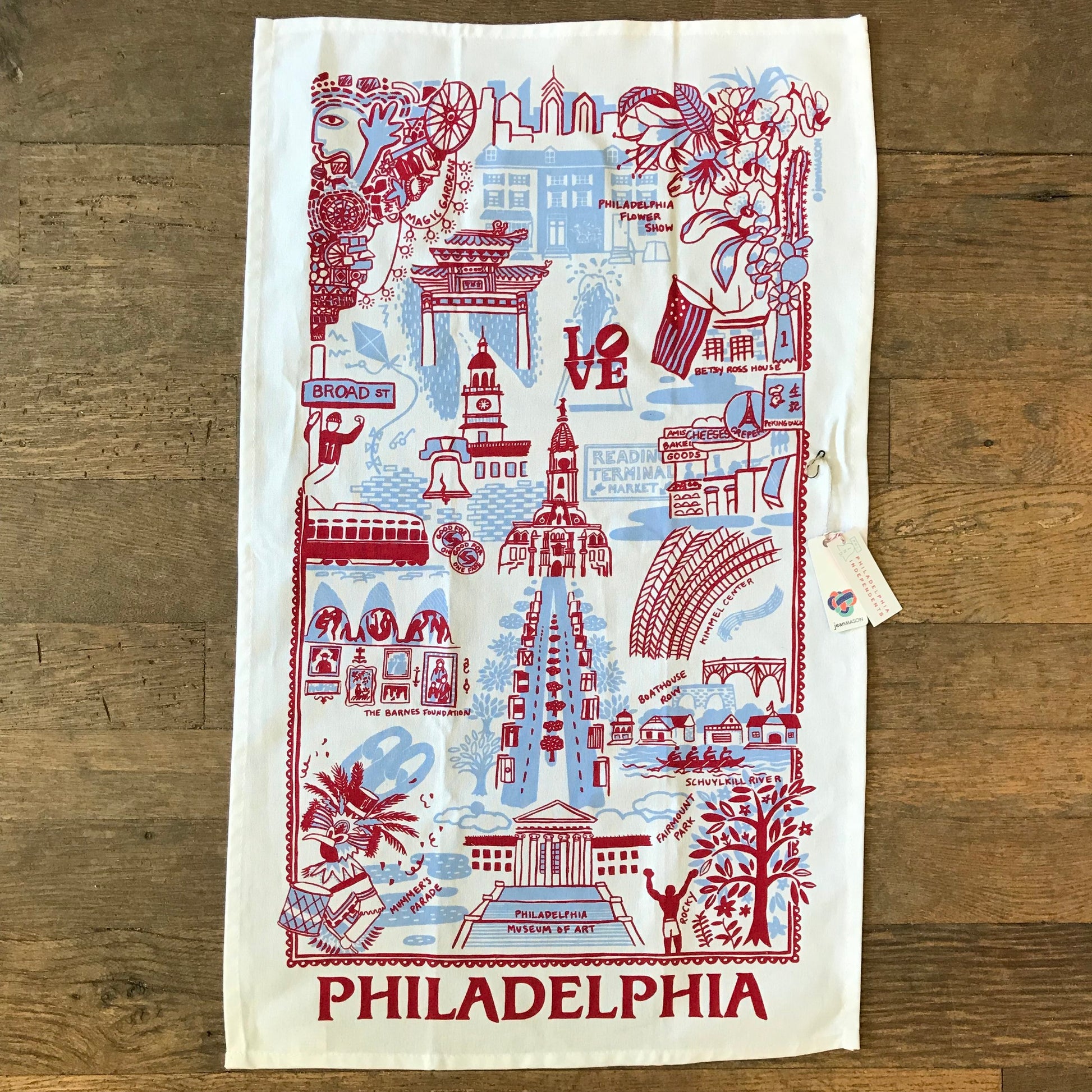 Decorative Philadelphia Tea Towel featuring iconic landmarks and symbols of Philadelphia in red and blue print, perfect as a host gift. Brand: Jean Mason