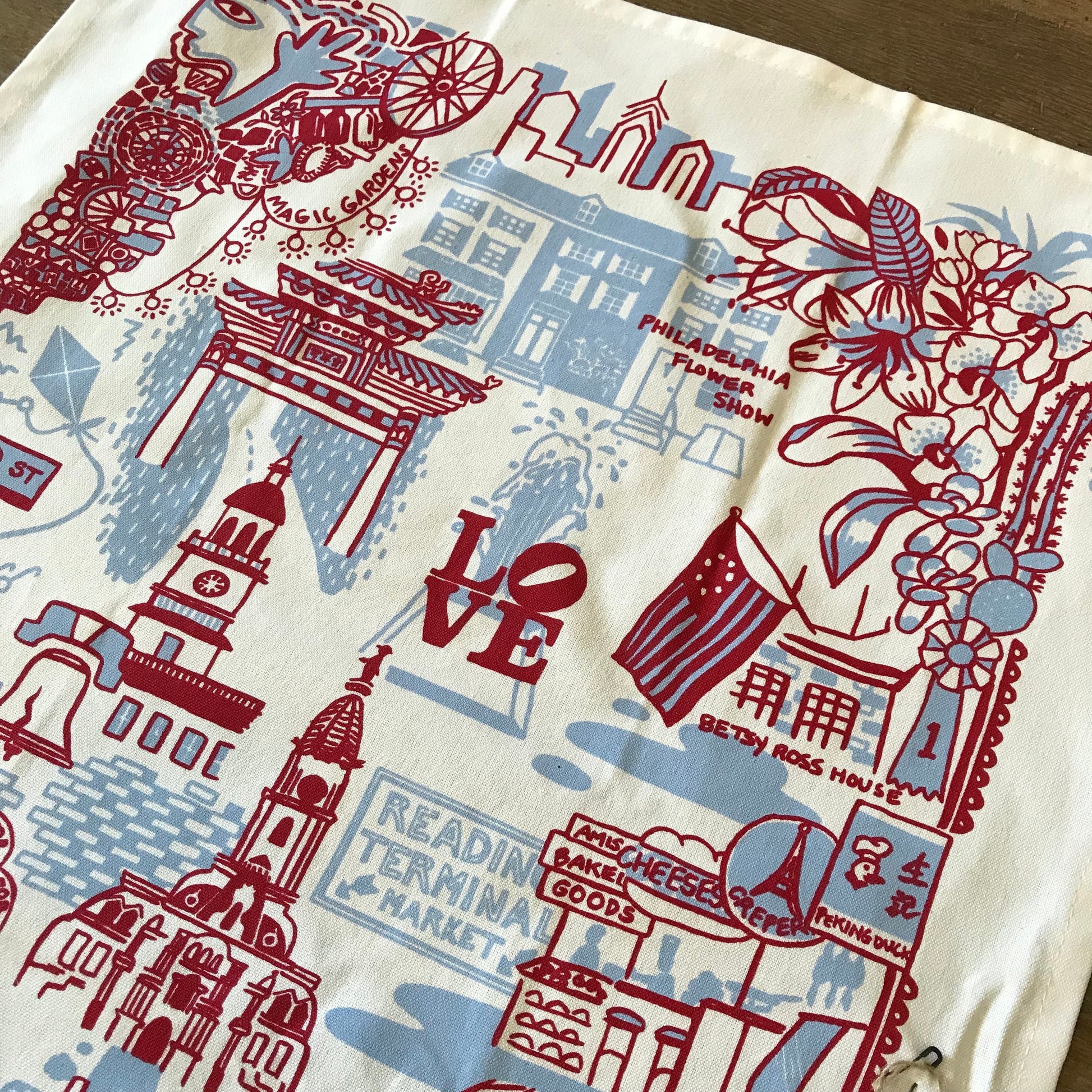 A Jean Mason Philadelphia Tea Towel with colorful illustrations showcasing Philadelphia landmarks and symbols.