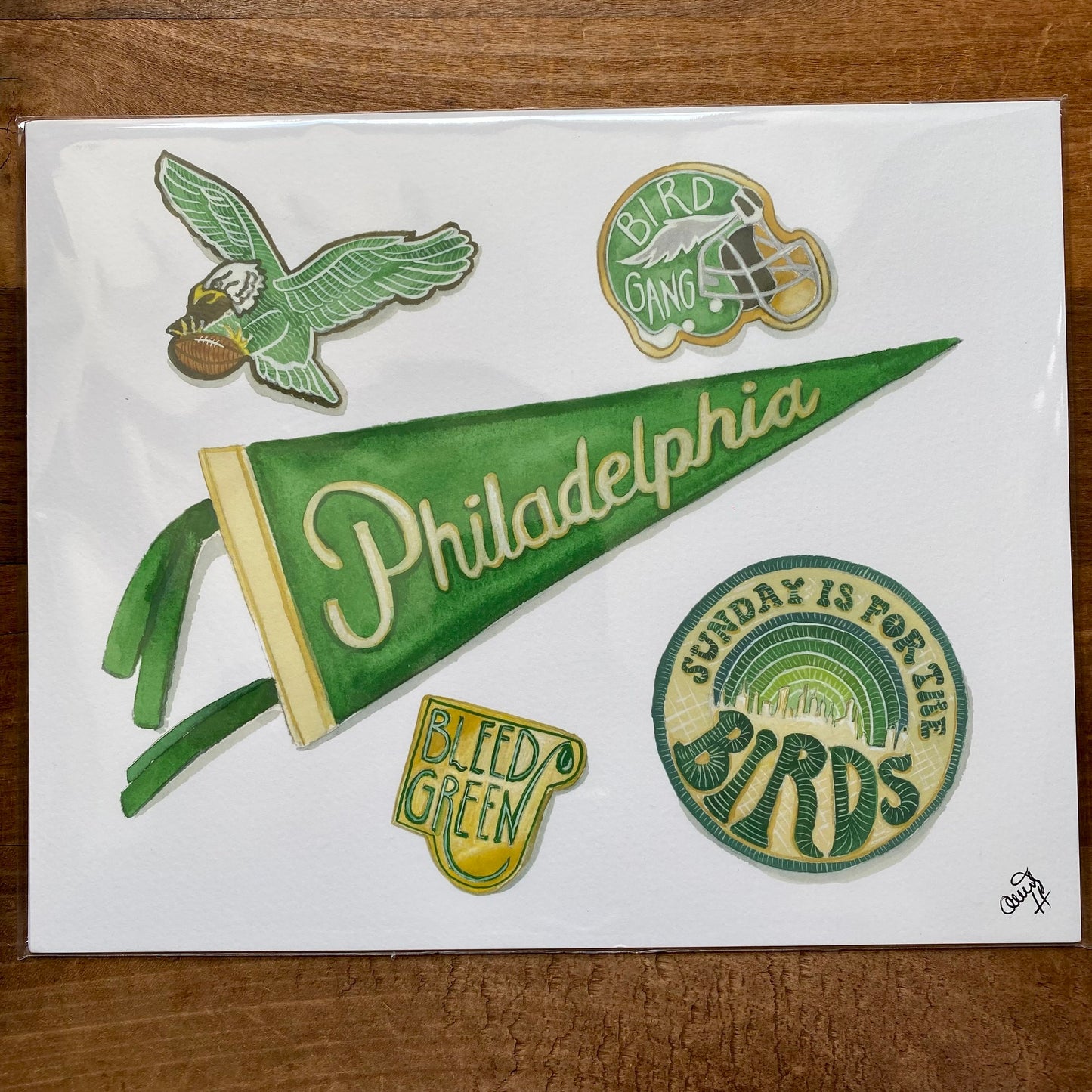 Hand-drawn artwork featuring Philly Sports Prints-themed illustrations, including a flying eagle, team pennant, and emblems with slogans, presented on fine art paper by Meadowbrook Lane.