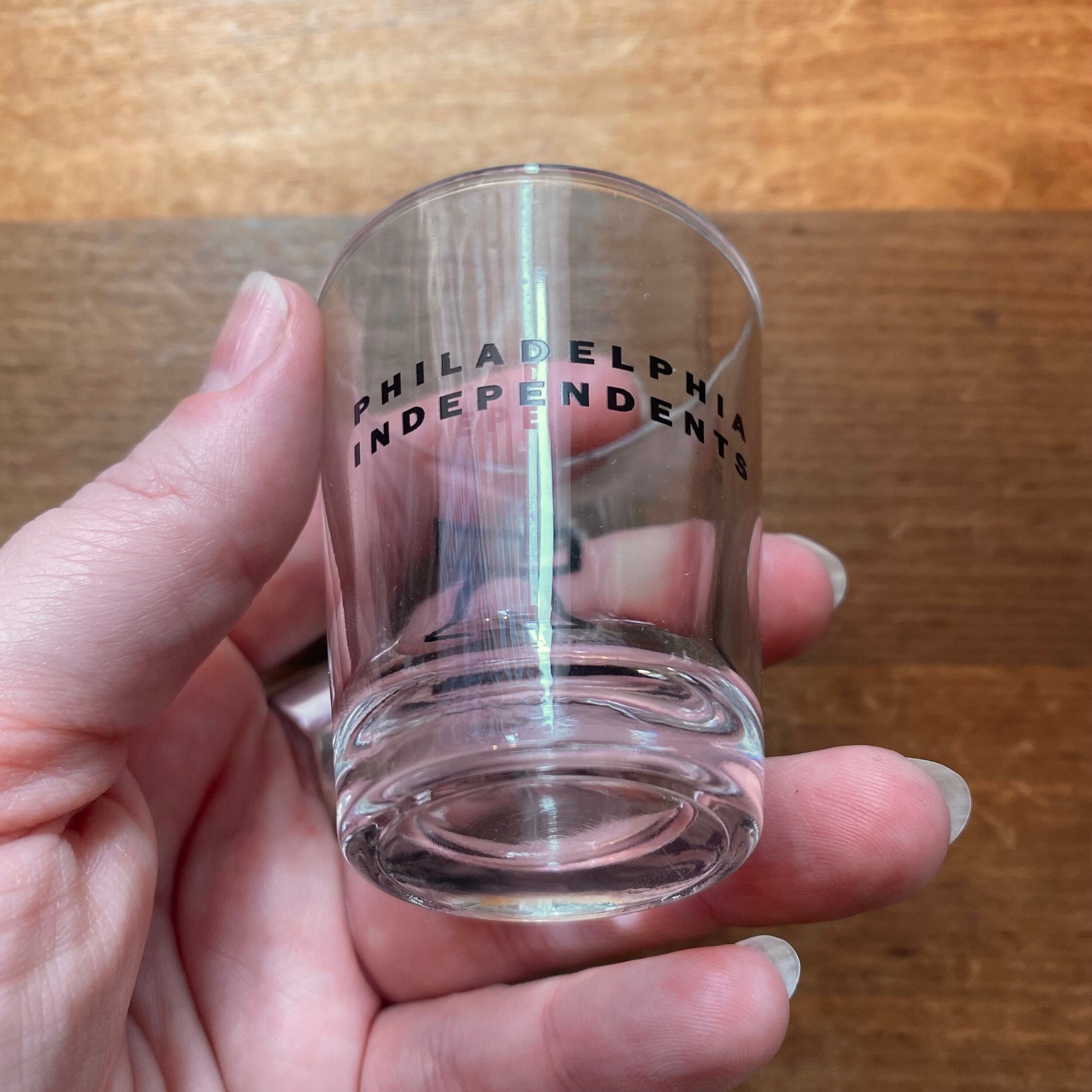 A hand holding a dishwasher safe Bell & Bolt shot glass with "Philadelphia Independents" text on it.