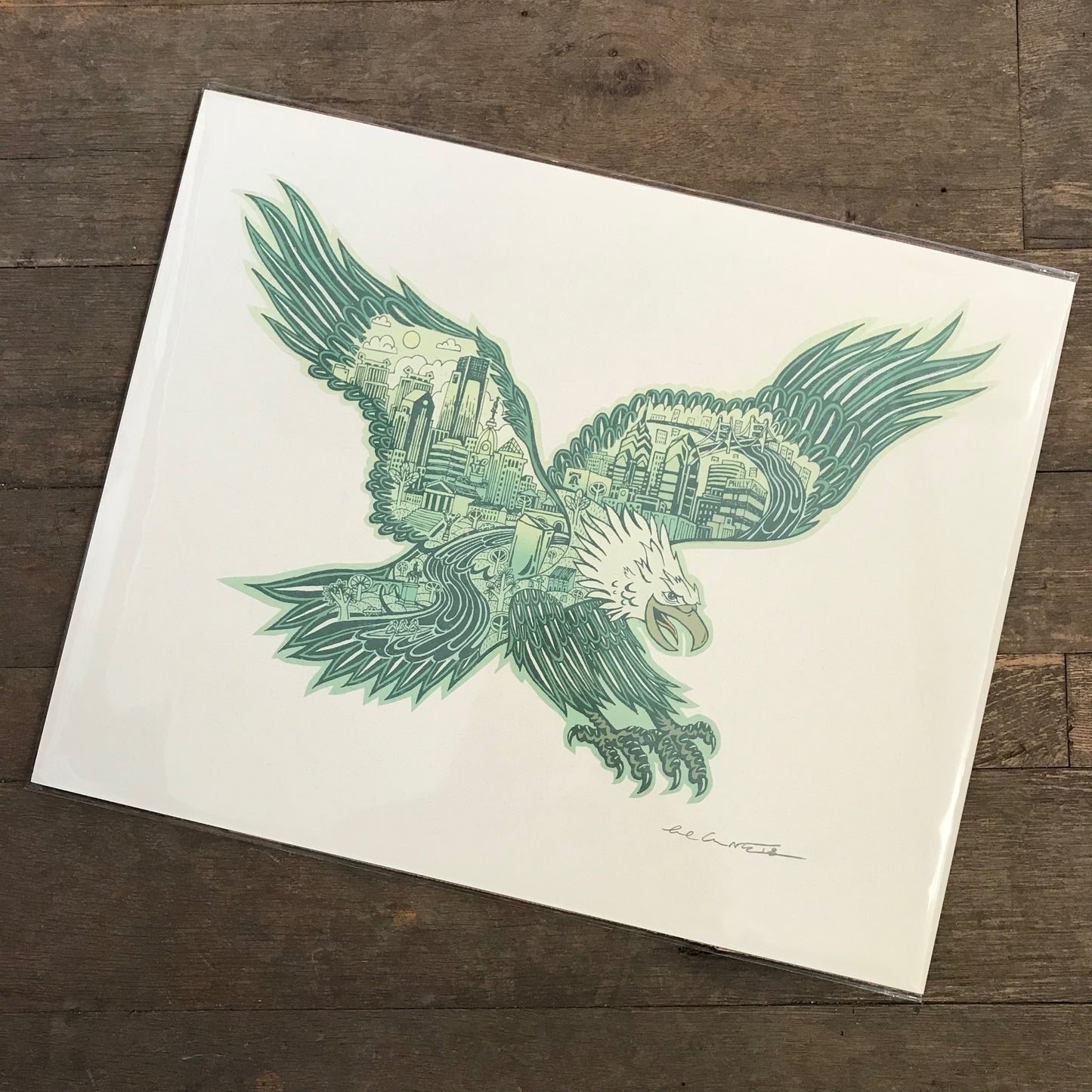 An illustration of a stylized Paul Carpenter Swooping Eagle Print with intricate patterns, depicted on a white paper displayed on a wooden surface.