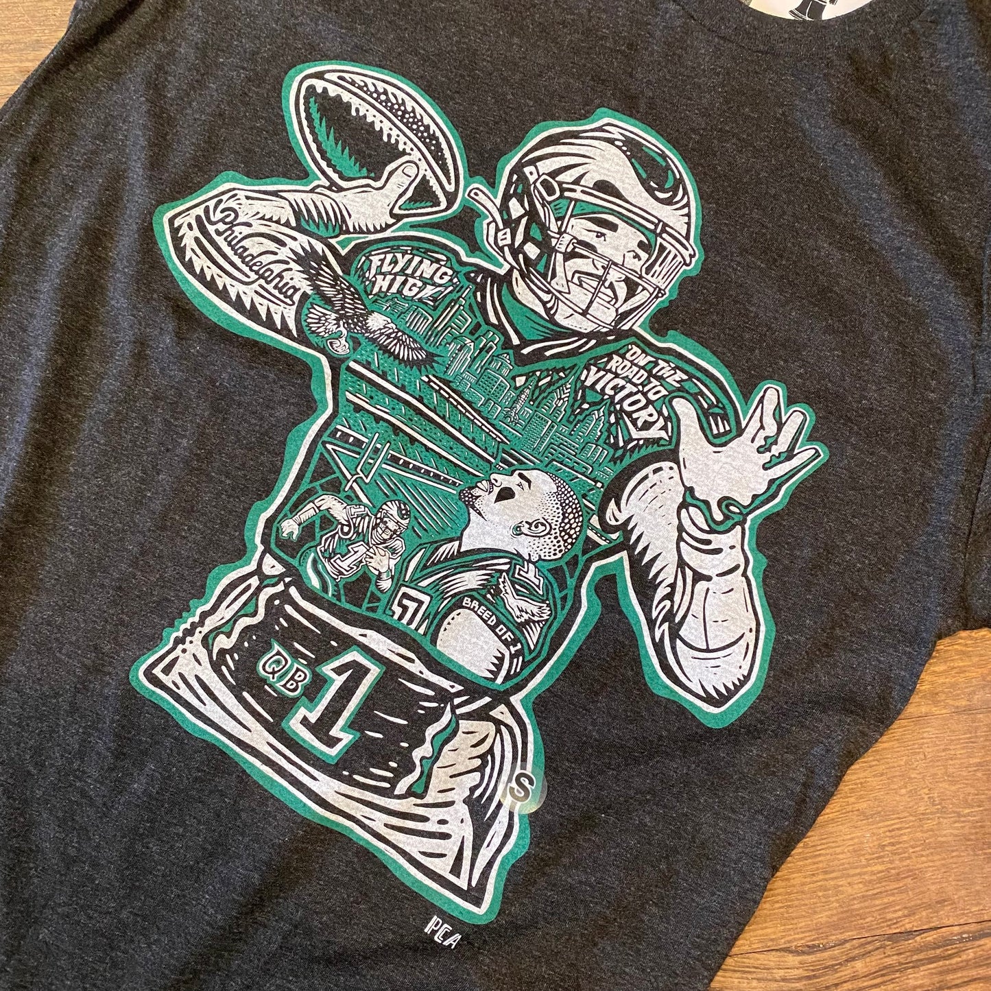 A black Jalen Hurts T-shirt featuring a graphic of Jalen Hurts in action, with stylized text and green accents by Paul Carpenter.