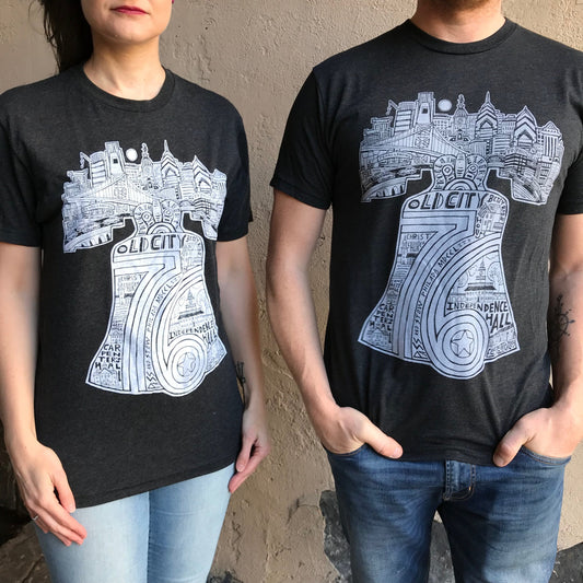 Two people wearing matching Paul Carpenter Liberty Bell T-Shirts with a graphic of a camera, the Liberty Bell, and Old City landmarks.