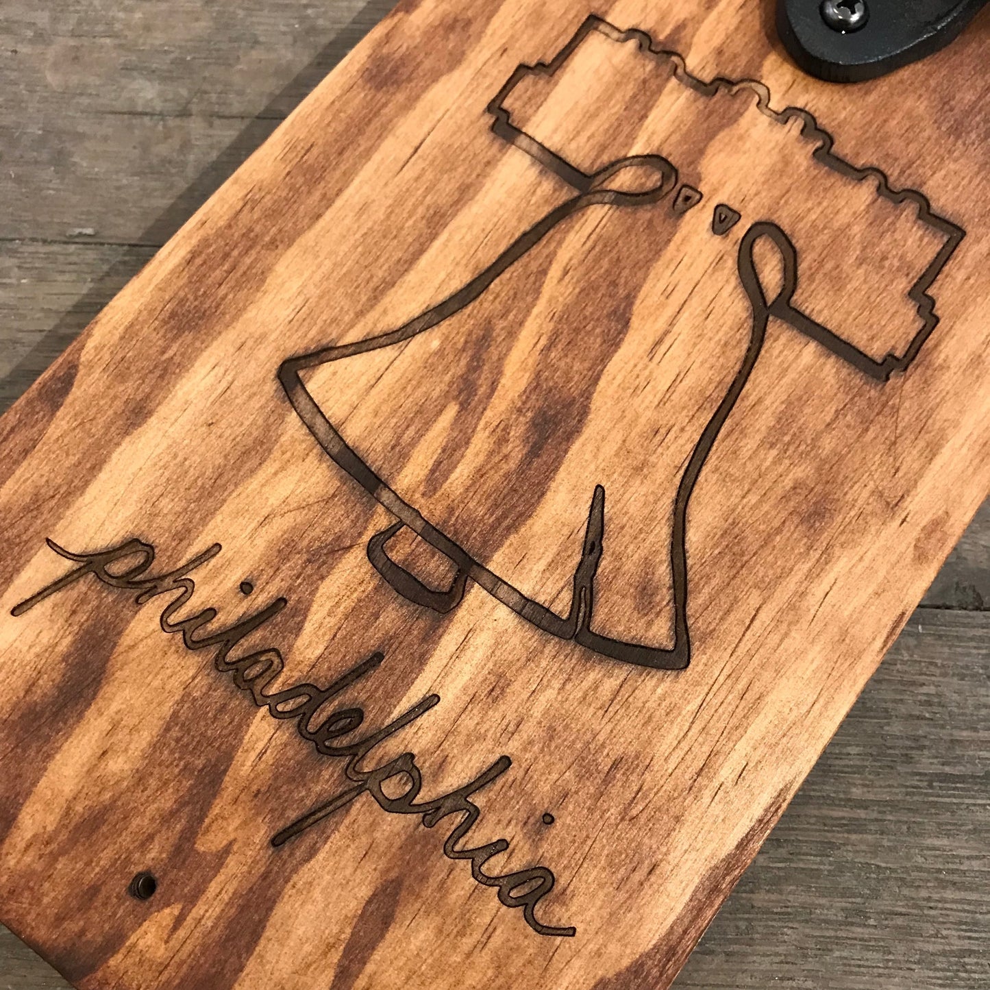 Wooden board with a detailed laser-etched engraving of the Liberty Bell and the word "Philadelphia" inscribed below it from Philly Phlights.