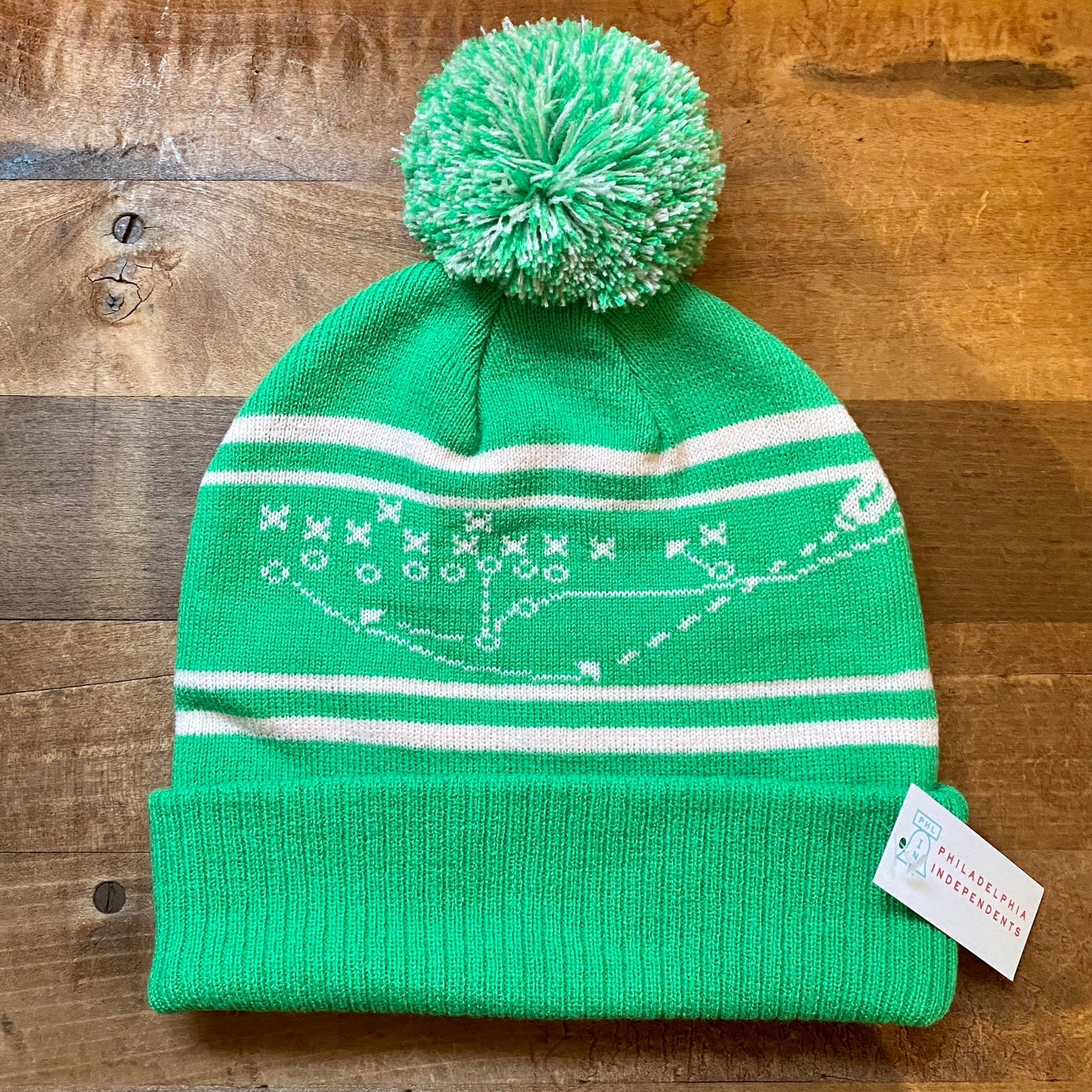 Green South Fellini Philly Special beanie with a pom-pom and a winter pattern, displayed on a wooden surface.