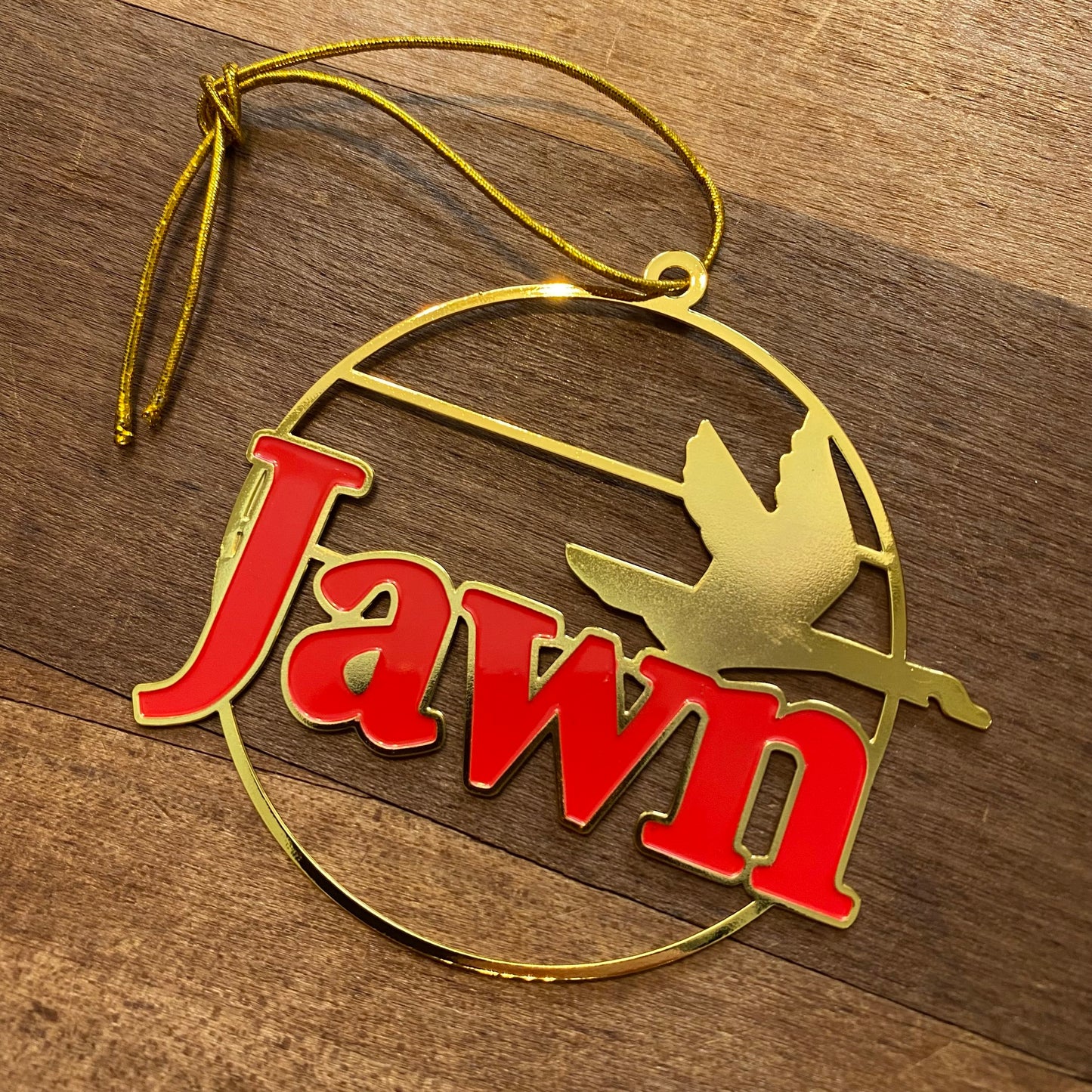 Gold and red South Fellini Jawn ornament with the word "jawn" and a silhouette of a flying bird.