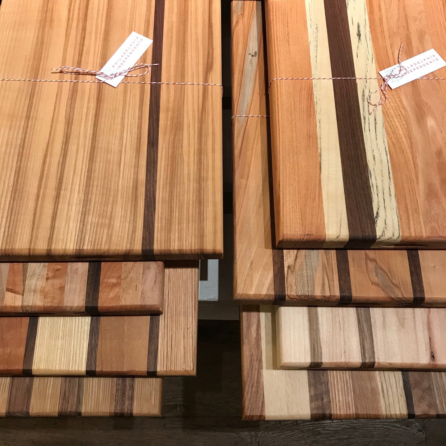 Stacks of Steve Reid Striped Wood Cutting Boards with labels attached by twine.