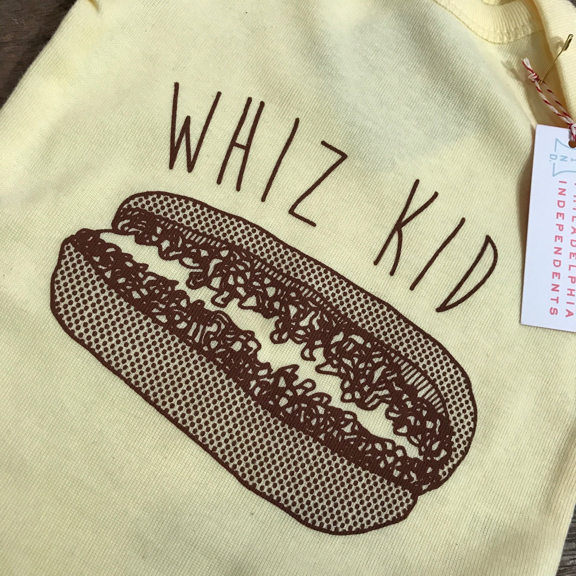 Yellow Whiz Kid Baby Onesie with "Philly genius" text and hot dog graphic, price tag attached by exit343design.